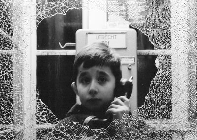 605237 Afbeelding van een jongen in een telefooncel te Utrecht, met een kapotgeslagen ruit.